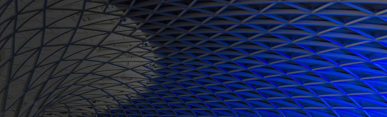 Abstract geometric ceiling pattern illuminated with blue lighting.