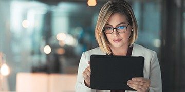 Photo of a woman reading information on a tablet.