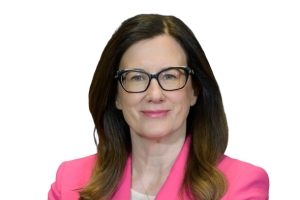 Head-and-shoulders professional portrait of Helen Lofthouse wearing glasses and a brightly coloured blazer, facing the camera against a plain light background
