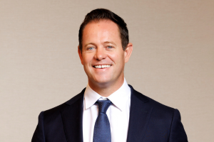  Head-and-shoulders professional portrait of Tim Whiteley with short hair, wearing a collared shirt and blazer, facing the camera against a plain light background