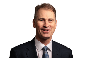 Head-and-shoulders professional portrait of Andrew Tobin wearing a suit jacket and tie, facing the camera against a plain light background
