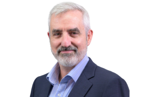 Head-and-shoulders professional portrait of Dirk McLiesh with short hair and facial hair, wearing a collared shirt and blazer, facing the camera against a plain light background