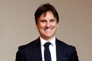  Head-and-shoulders professional portrait of Tim Whiteley with short hair, wearing a collared shirt and blazer, facing the camera against a plain light background