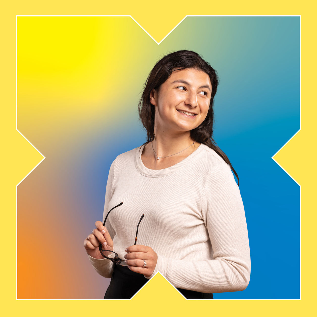 A square photograph of a woman in a white top smiling over her shoulder