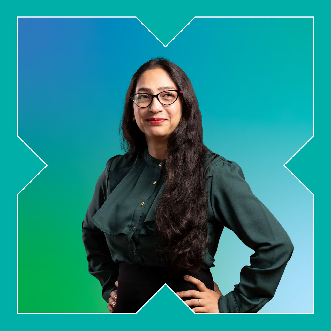 A square photograph of a woman with her hands on her hips smiling ahead.