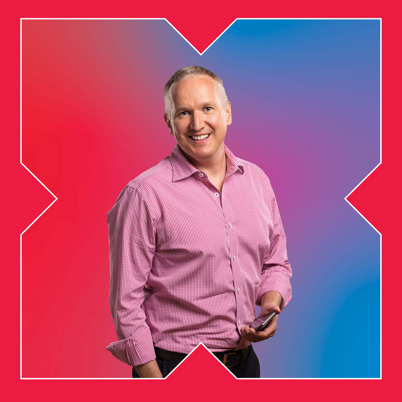 A square photograph of a man in a pink top smiling down the camera.