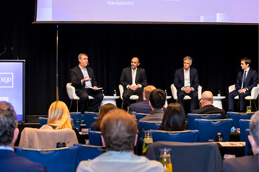 Panel of speakers seated on a stage facing an audience