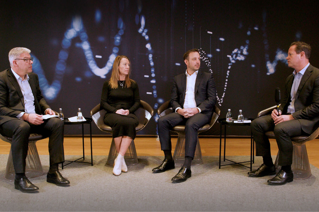 Panel of speakers seated on a stage in front of an audience