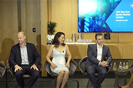 Panel of speakers seated on stage chairs in front of a presentation screen