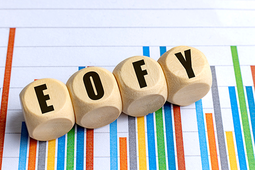 Wooden cubes with the letters EOFY are arranged in a row on top of a printed bar chart.
