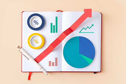 An open notebook displays colorful business analytics elements arranged neatly on its pages.