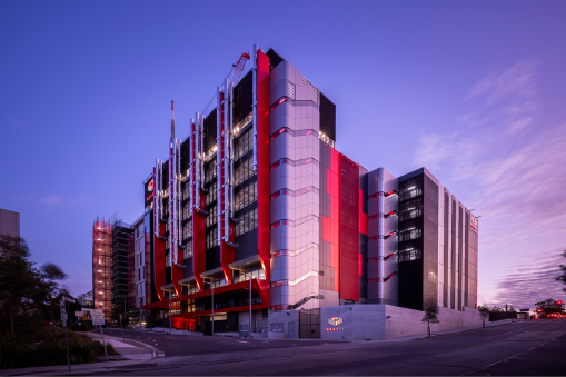 NEXTDC data centre facility with modern warehouse-style buildings and a gated entrance at sunset.