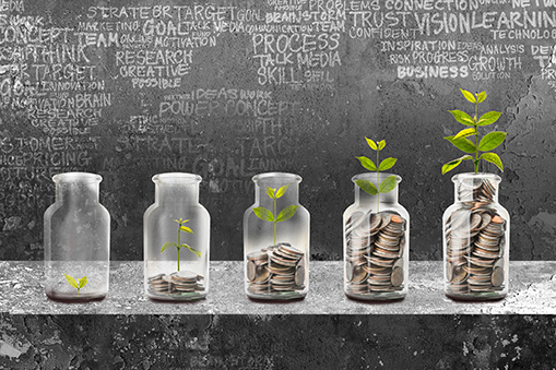 Five glass jars arranged in a row from left to right, each progressively filled with stacked coins and a growing green plant, positioned on a concrete surface against a dark textured background featuring faint business-related words