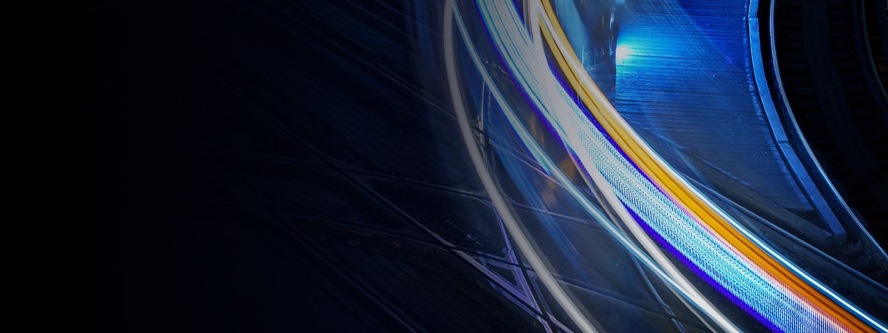 Abstract image of curved blue, white, and orange light trails flowing across a dark background with a bright area in the upper right.