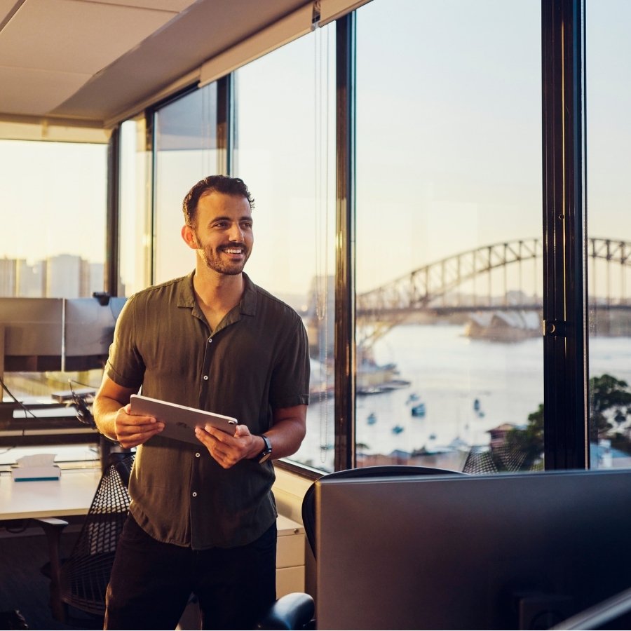 Interior office workspace with desks and windows overlooking Sydney Harbour and the Harbour Bridge, used as a visual representation of property‑related investment context.