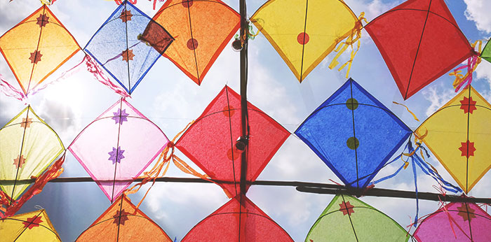 Colourful diamond-shaped kites suspended against a bright sky.