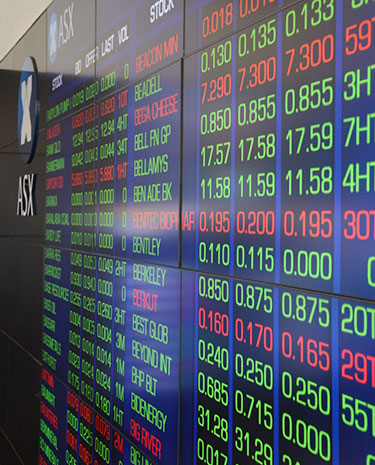 Electronic display board showing stock codes, prices, and market data in rows of red, green, and white numbers.