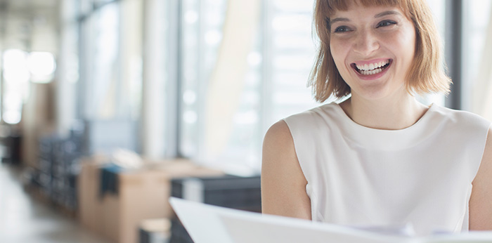 Person seated in an office holding a document during a workplace discussion.